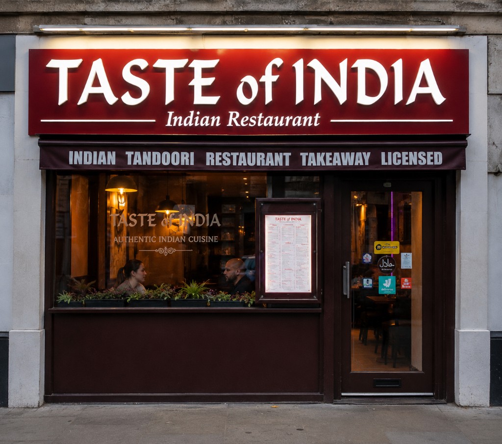 Taste of India shopfront on Queensway, with gold lettering on a burgundy facade